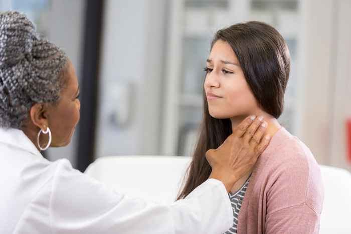 female doctor examining young woman's neck